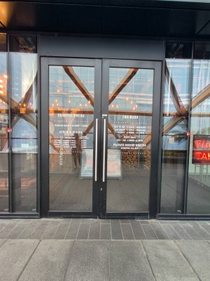 Glass doors with black, wooden doors ahead. Pull silver handles in middle to open.