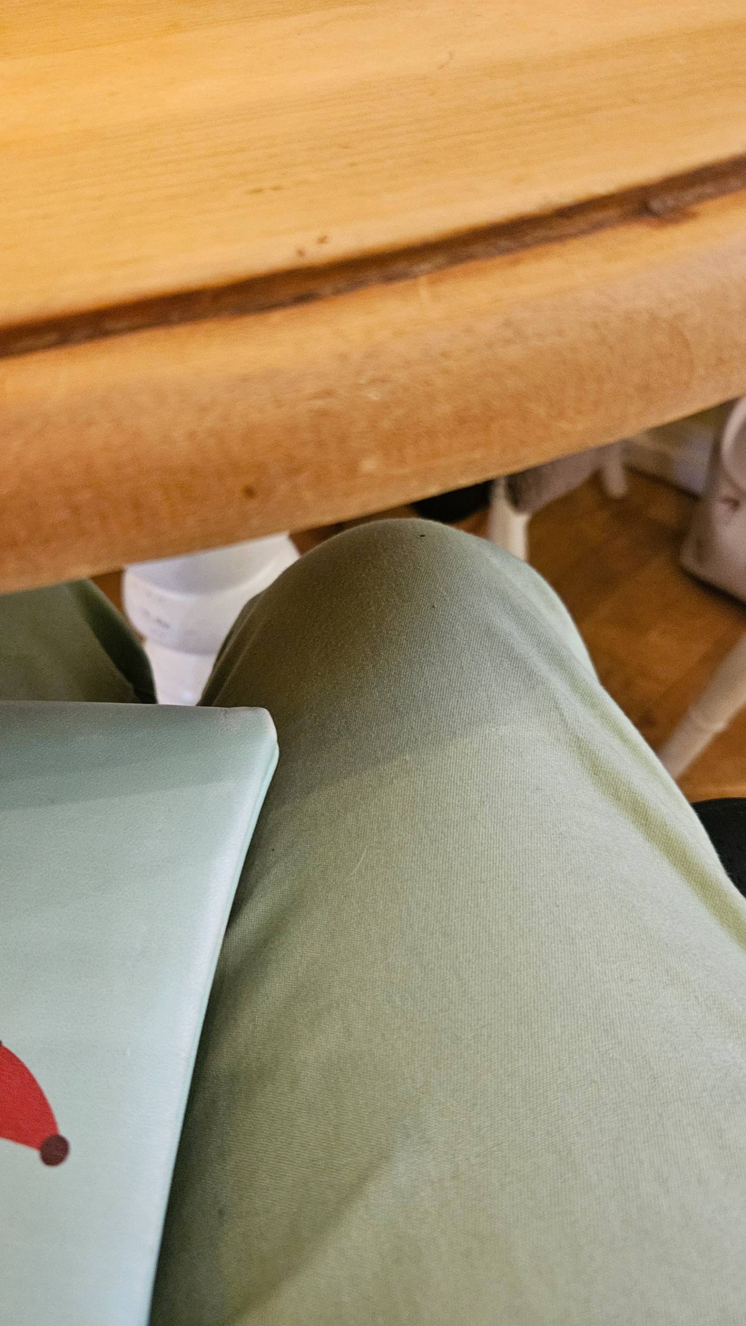 A wooden table with a knee underneath demonstrating the table height