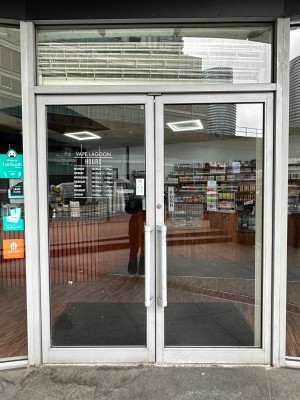 Double glass doors with silver doorframe. Long handle in the center. Push to open.