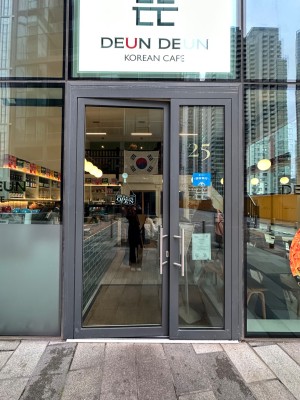 Glass doors with grey frame and silver handles. Push from centre to open.
