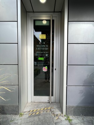 Glass door with grey frame. Push metal handle on right to open.