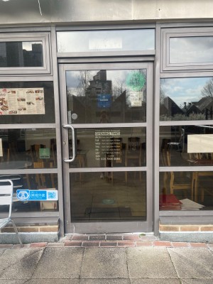 Glass door with grey frame ahead. Pull vertical handle on left to open.