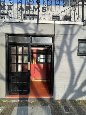 Step leads to black doors with glass panels. Push from centre to open.