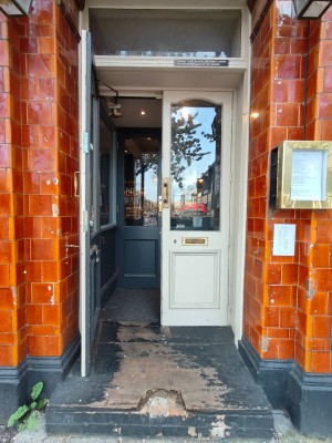 Double white glass doors leading to another double door. Pull golden handle in centre to open.