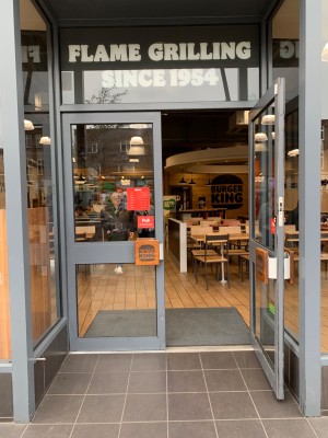 Double glass doors with grey metal frame ahead. Pull from handles in centre to open.