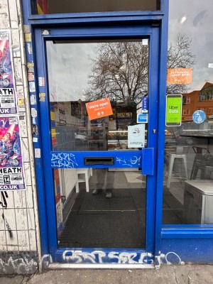 Single glass door with bright blue metal frame. Push handle on right to open.