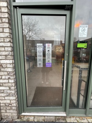 Single glass door with green frame. Pull vertical silver handle on right to open.