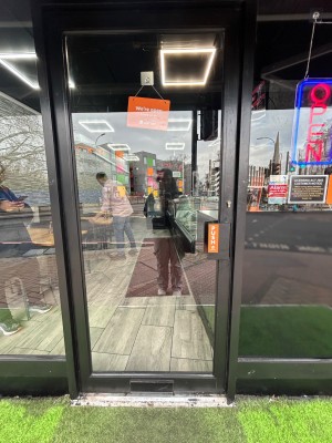 Single glass door with black frame. Push handle on right to open.
