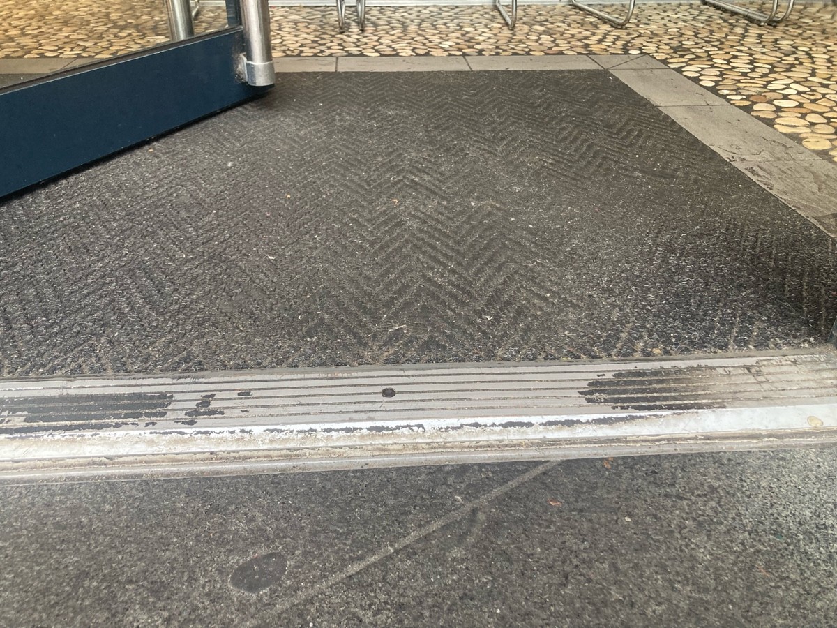 Metal bump at foot of door followed by doormat.