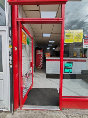 Facing entrance door. Red framed glass door. Push red handle on right to open.