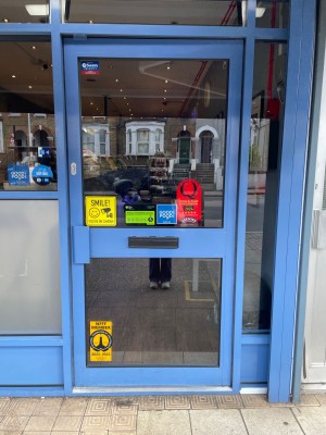 Single glass door with blue frame. Push vertical handle on left to open.