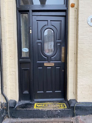 First black wooden glass panelled door. Push from right to open.