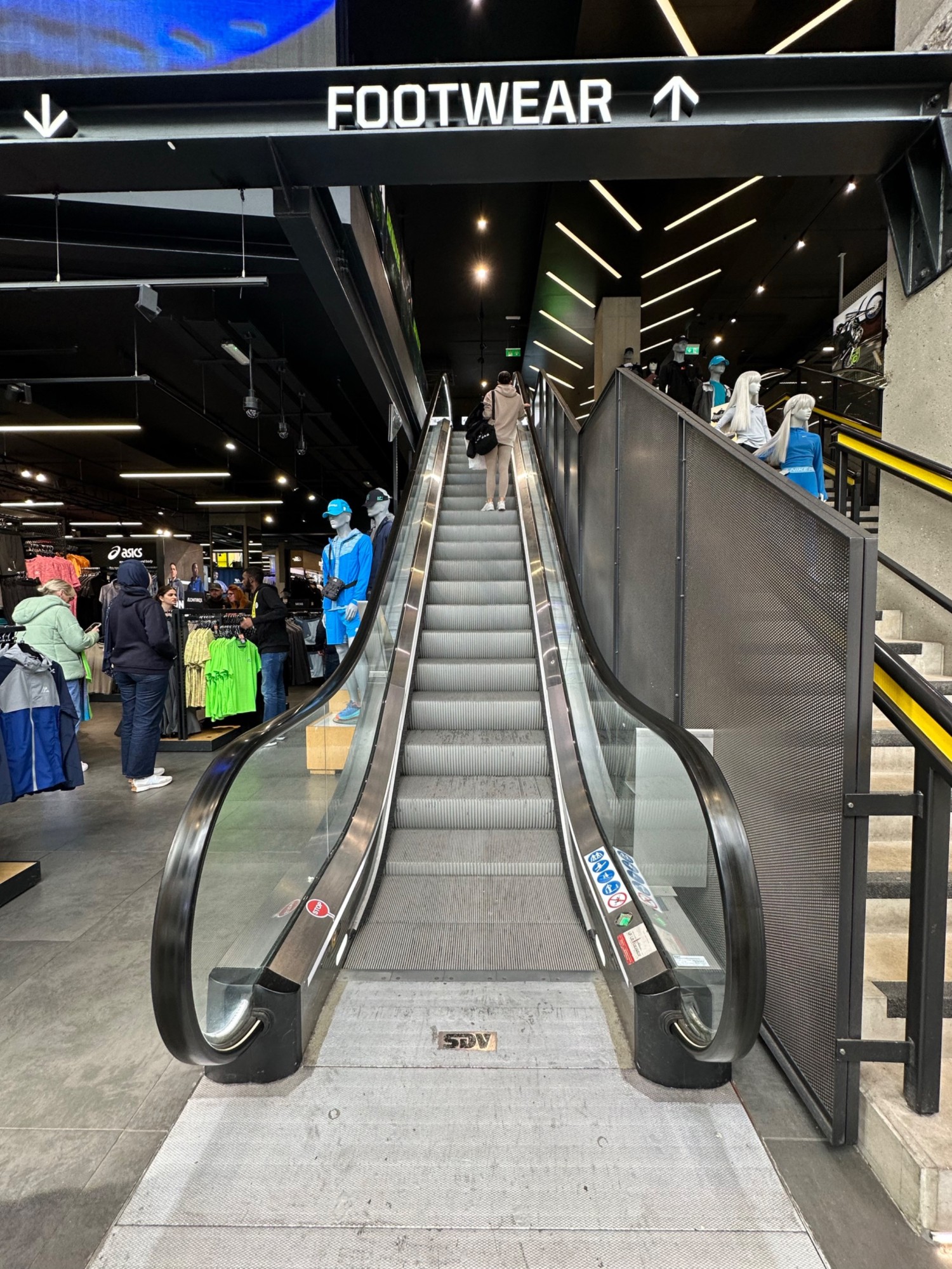From foot of escalator facing straight. Moving black handrail on left and right.