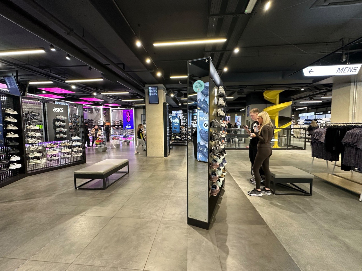 From first pillar facing right. Shoe display ahead. Path on left and right of display with benches either side. Clothes rack on right. Shoes on left.