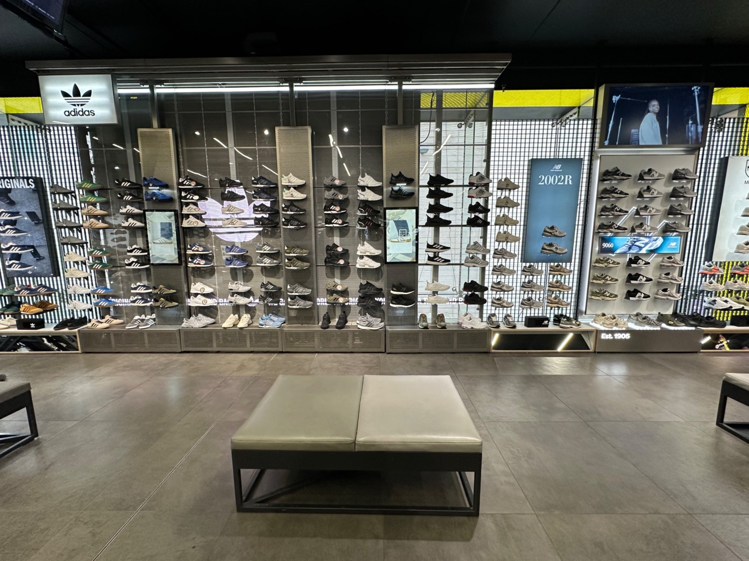 From past first pillar facing straight. Benches spaced out evenly ahead, and to left and right. Shoe display along back wall ahead.
