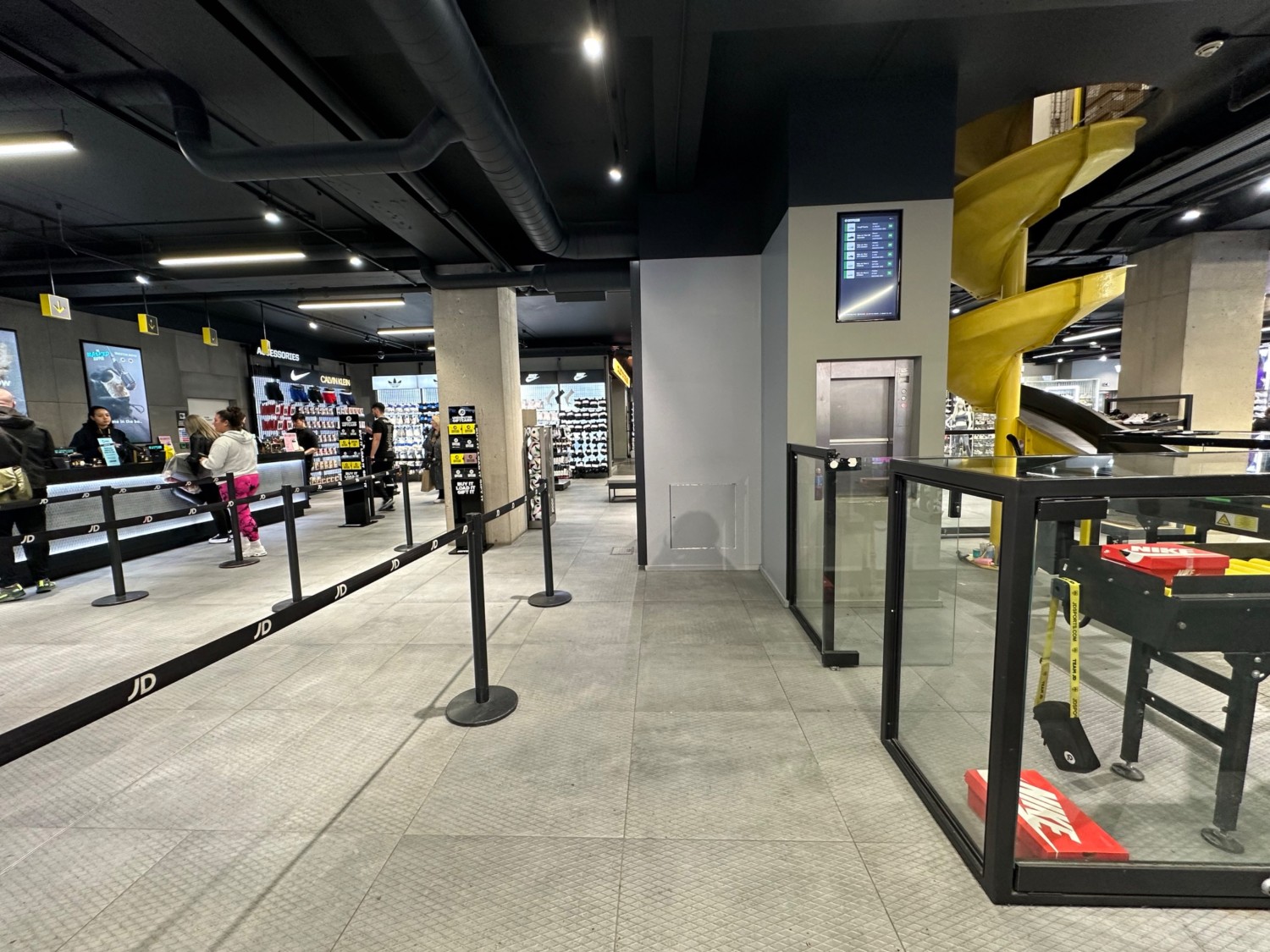 From corner of shoe slide display facing right. Slide on right. Divider on left. Path ahead goes left past divider to queue area for till.
