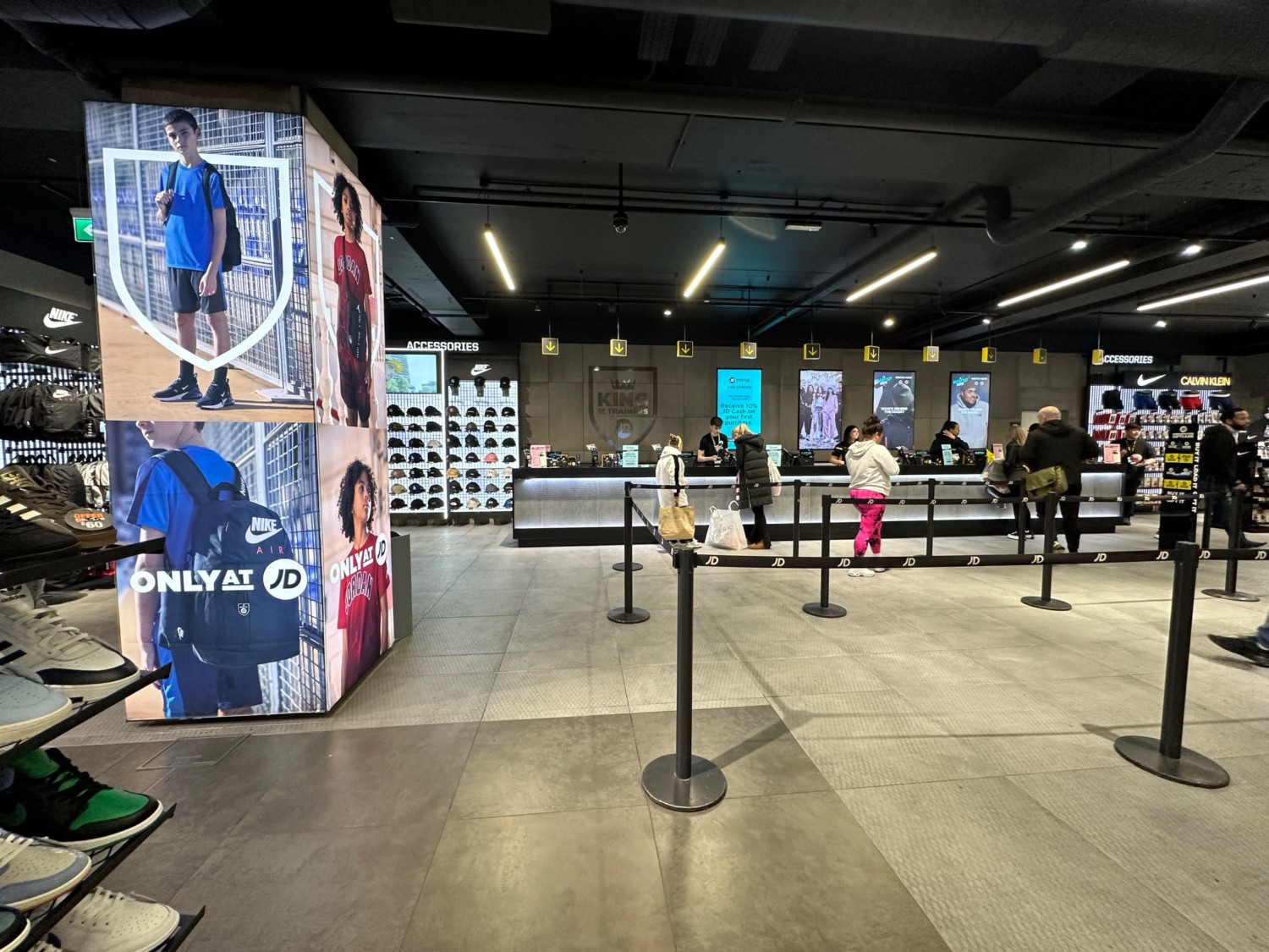 From end of shoe slide display facing straight. Shoe display on left. Third pillar and end of shoe display to far left. Till and queue area on right.