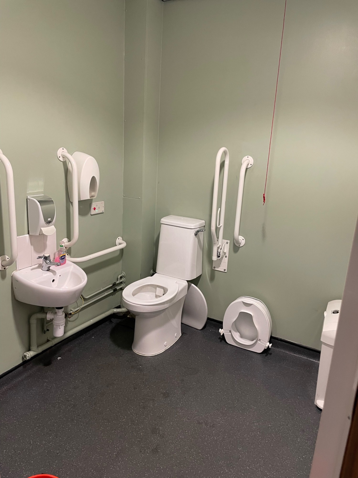The cord has been replaced since this photo was taken. There is a wheelchair height hand dryer as well as paper towels. No changing table or hoist.