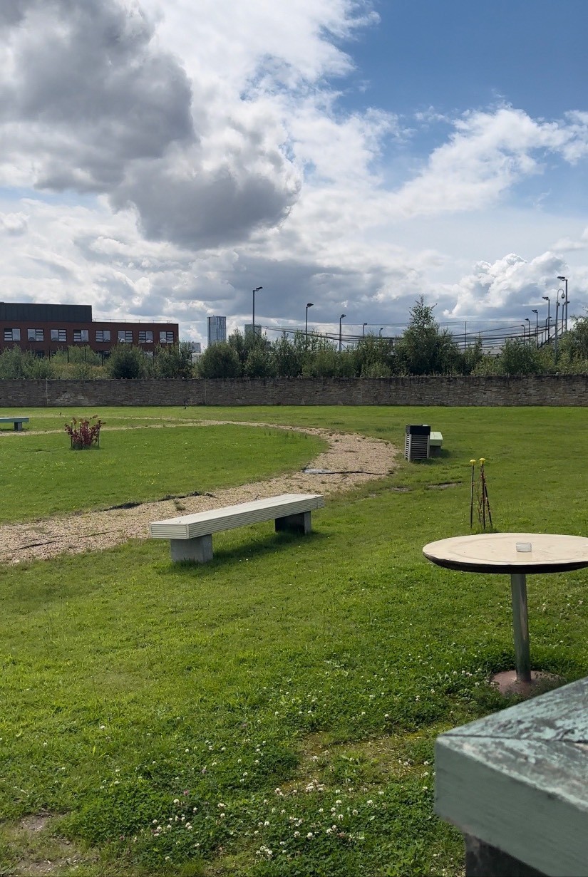 View of the benches and the dirt path. Open top dustbins and roll under tables in shot too.