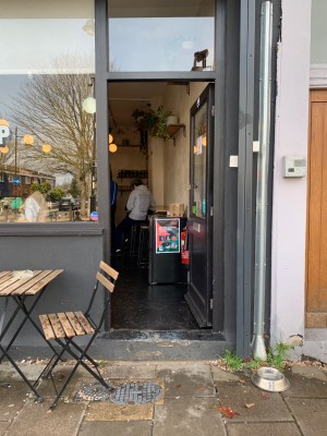 Black wooden door with glass panel. Push from left side of door to open.