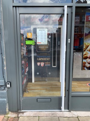 Glass door with grey metal frame ahead. Push door from handle on right to open.