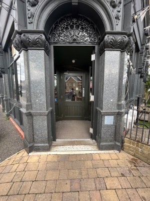 Black wooden door ahead. Push from left to open.