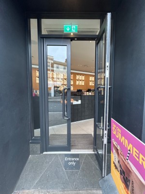 Double glass doors with black frames. Pull vertical black handles in middle to open.