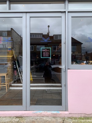 Glass door with grey metal frames ahead. Push handle on right to open.
