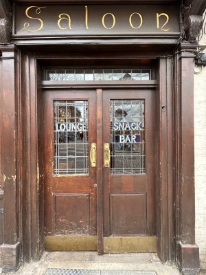 From further right of main entrance, facing venue. Double wooden dark brown doors with glass panels. Push handles in middle to open.