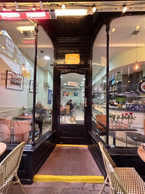 Glass open archway with black metal frame on front. Black wooden frame glass door after. Metal handle on right. Pull to open.
