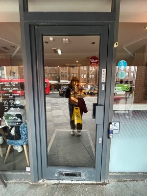 Single glass door with grey frame. Pull handle on right to open.