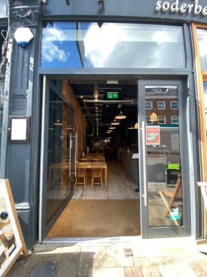 Glass door with grey metal frames ahead. Push handle from right to open.