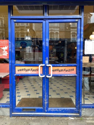 Double glass door, with blue doorframe. White handles at centre of door. Pull to open.