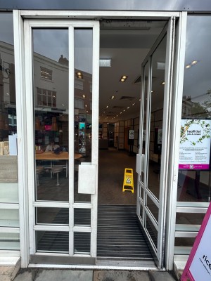 White framed glass door with white metal handle in centre. Push from centre to open.