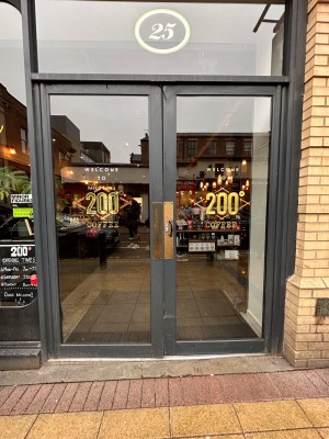 Glass double doors with grey metal doorframe. Push from centre to open.