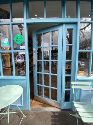Glass door, with light blue doorframe. Silver handle on left. Pull to open.