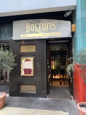 entrance to the restaurant through narrow double doors which lead down stairs into the restaurant with twin doors with glass panels and bronze handles