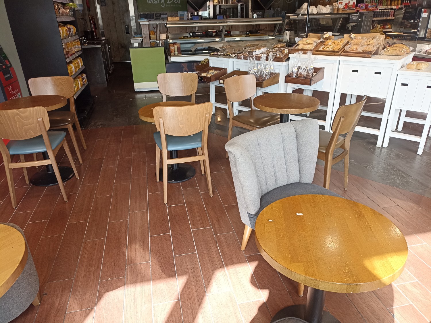 Few tables at the window in the front left corner of the shop, close to the coffee machine.