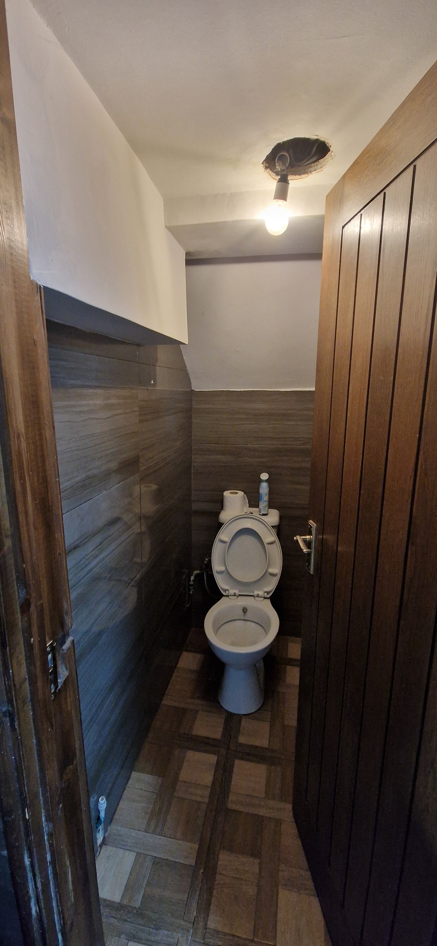View of cubicle from outside. Pattened walls, turn bar handle on door. Small space. Door opens inwards.
