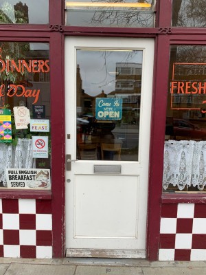 White framed half panel glass door ahead. Push from handle on left to open.