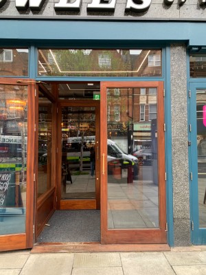 Double glass doors with wooden doorframe ahead. Gold handles at centre. Pull to open.