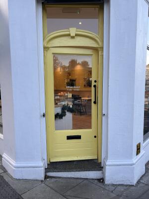 Yellow wood-framed glass door. Push from black handle on right to open.