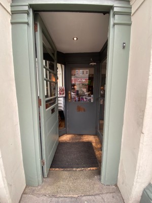 Light blue wooden door, with glass panel. Push on right to open.