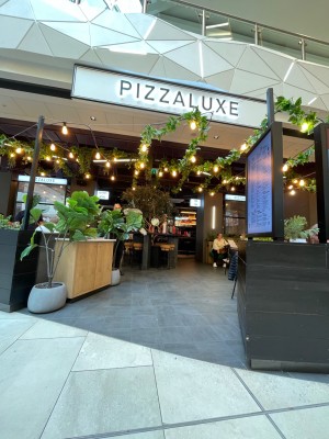 Open entrance with a large screen menu to the right. Plant and counter with menus on the left.
