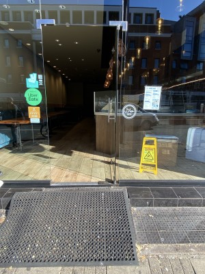 Glass door with silver metal handle on left. Push from left to open.