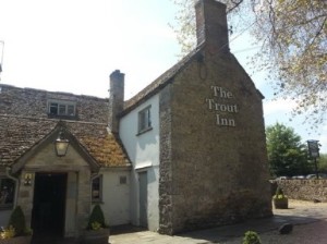 The front entrance of the Trout inn. It has a cobble-type path. The inn is an old style building with the words ‘the trout inn’ on the wall.