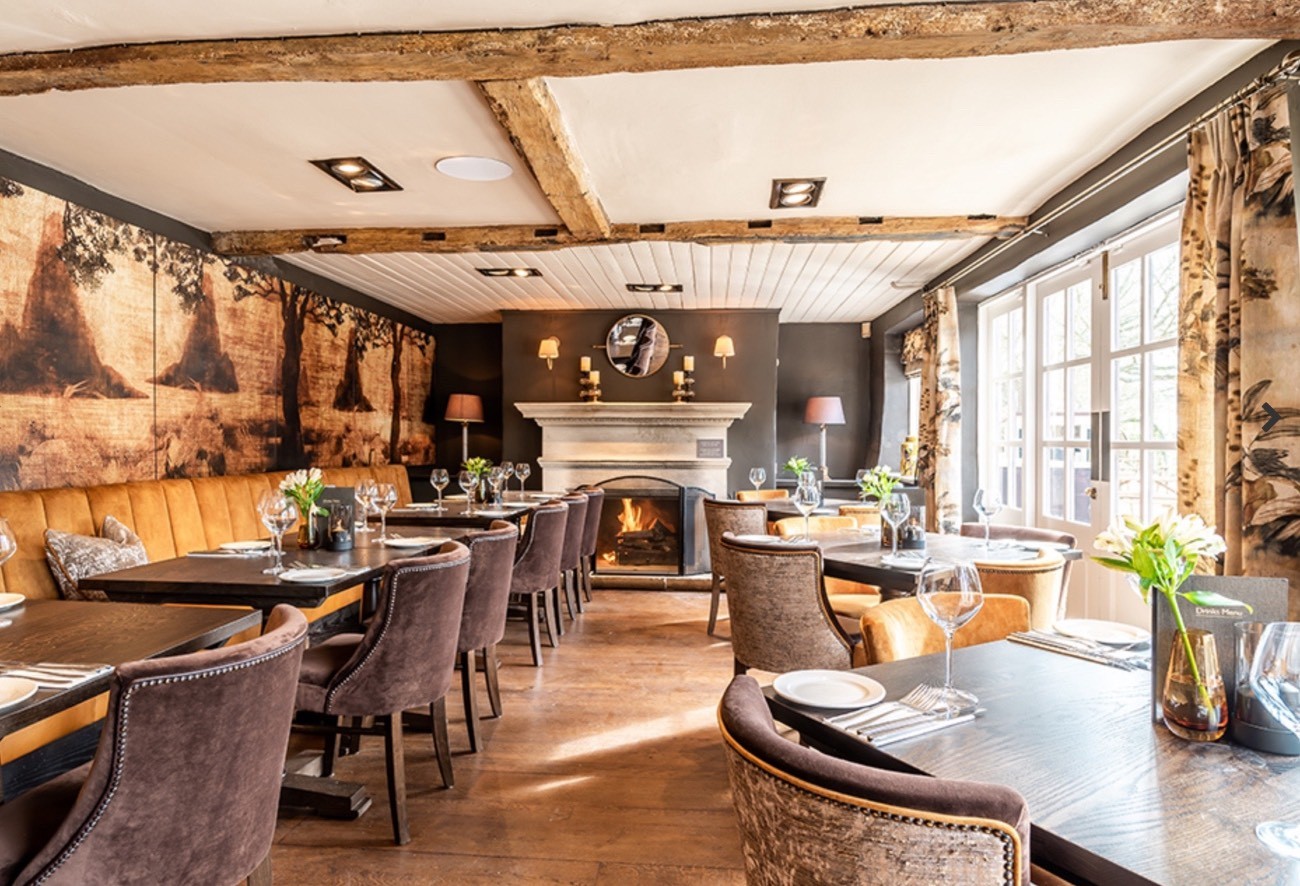 Dining area. On the left is a long padded bench with tables. On the right are round tables for 4.