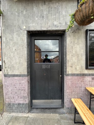 Black framed glass panelled door. Push from right side to open.