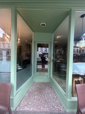 Green frame archway in front. Glass walls along both sides. Green frame glass door at back.