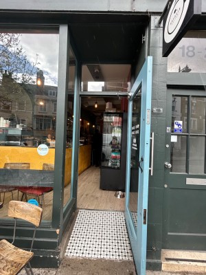 Green open archway, followed by single glass door with blue frame. Pull silver vertical handle from left to open.